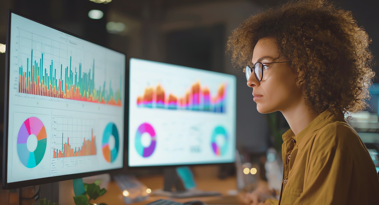 Analyste data examinant des graphiques colores sur deux ecrans d'ordinateur