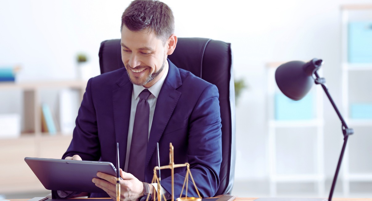 Avocat en costume consultant une tablette à son bureau