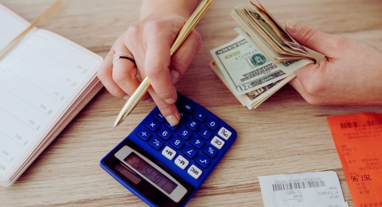 Personne calculant ses revenus avec une calculatrice des billets et des recus