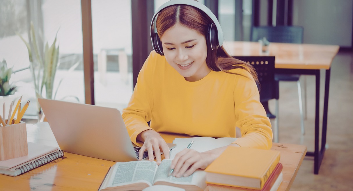 Etudiante souriante revisant avec un ordinateur portable et des livres