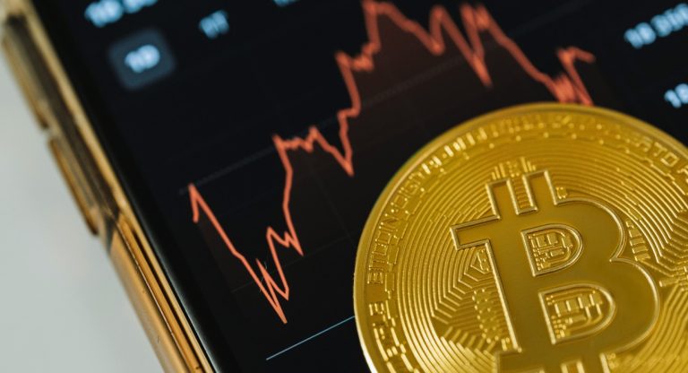 Pièce de bitcoin devant un graphique de marché volatil en rouge
