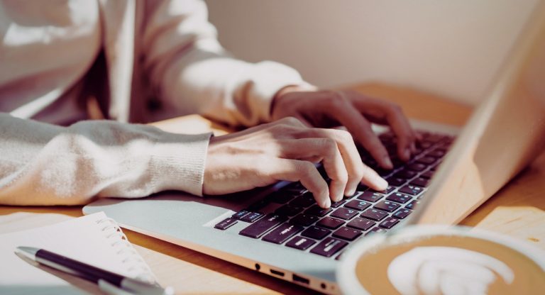 Mains tapant sur le clavier d un ordinateur portable a un bureau avec un cafe