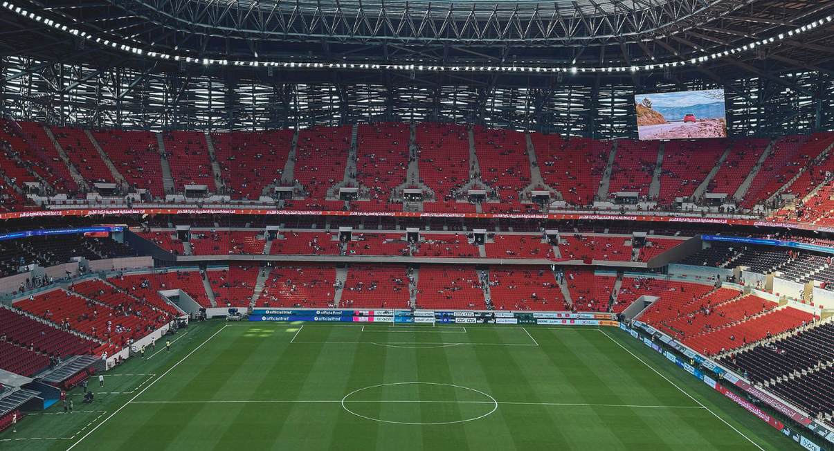 Stade de football moderne avec pelouse verte et tribunes avant un match